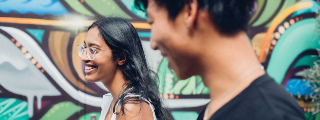 Girl and boy smiling past mural